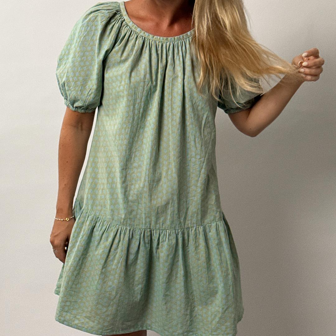 Woman wearing a green dress against a plain background