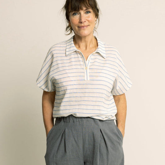 Woman wearing a striped shirt and gray wide-leg pants against a plain background