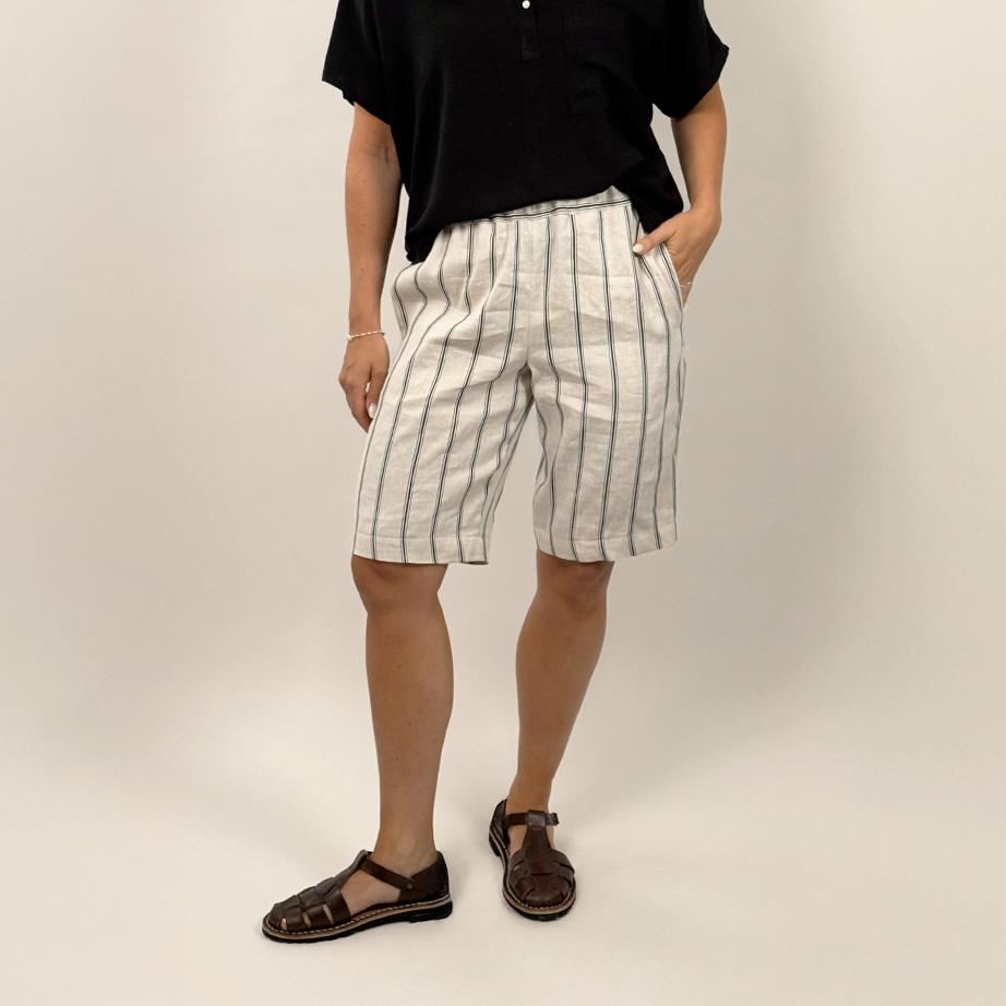 Person wearing a black shirt and striped shorts on a plain background