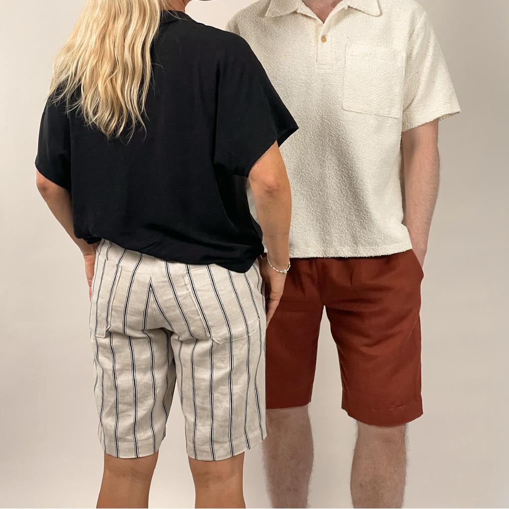 Two people standing side by side wearing casual clothing against a plain background