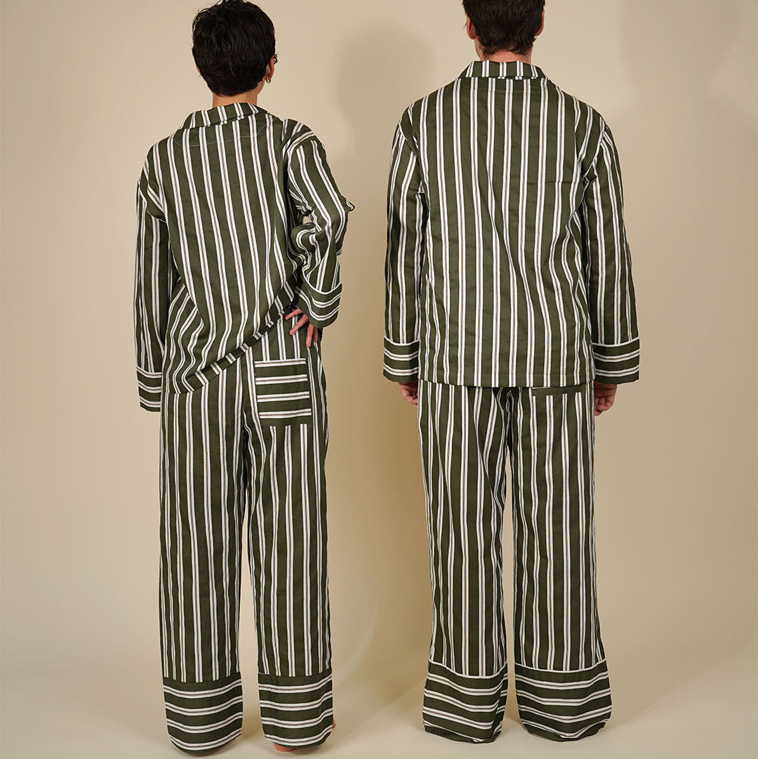 Two models shown from the back wearing matching striped pajama sets in olive green and white, standing against a plain beige studio background.