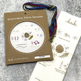 Kraft board packaging with cream cotton stitch sampler and hank of cotton embroidery floss in winter color palette
